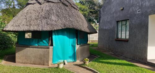 a small blue building with a thatched roof at The Best Green Garden Guest House in Harare in Harare