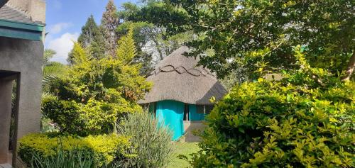 a thatch roofed house with a blue door at The Best Green Garden Guest House in Harare in Harare