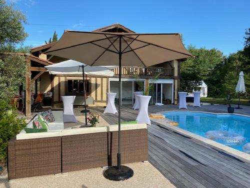 a large umbrella sitting next to a swimming pool at maison de vacances Mont de Marsan in Lucbardez-et-Bargues