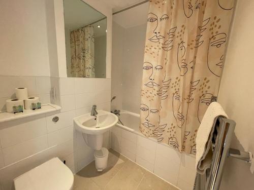 a bathroom with a toilet a sink and a shower curtain at Quality City Leicester in Leicester