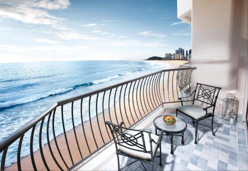 a balcony with two chairs and a table and the ocean at Paradise Hotel Busan in Busan