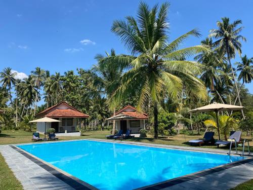 een zwembad tegenover een resort met palmbomen bij Ambarella Lodge - Katunayake in Hunumulla
