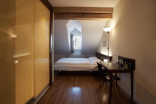 a small bedroom with a bed and a desk in a room at Goldener Schlüssel in Bern