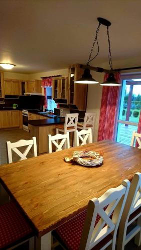a kitchen with a wooden table and white chairs at Dům a chatka pod Smrkem in Nové Město pod Smrkem