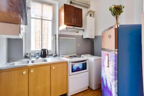 une petite cuisine avec un évier et un réfrigérateur dans l'établissement Appartement meublé quai de Seine, à Ivry-sur-Seine