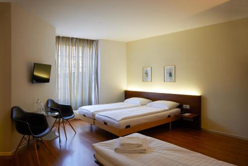 1 Schlafzimmer mit 2 Betten, einem Tisch und Stühlen in der Unterkunft Goldener Schlüssel in Bern
