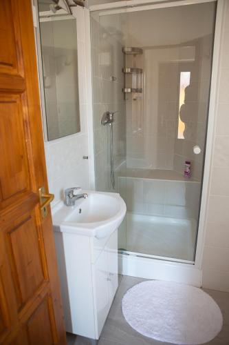 a white bathroom with a sink and a shower at Hunyadi Panzió-Apartman in Makó