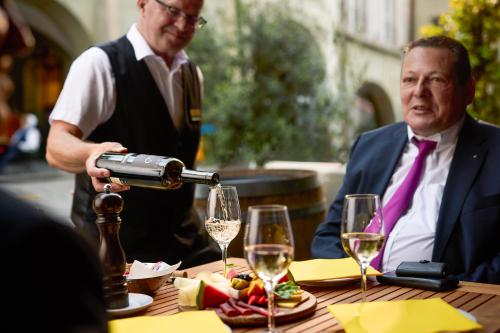 two men sitting at a table with glasses of wine at Goldener Schlüssel in Bern