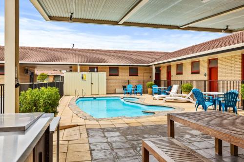 a patio area with chairs, tables, and a pool at Comfort Inn Glenelg in Adelaide