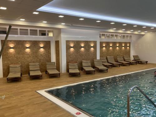 a pool in a hotel lobby with chairs and a swimming pool at Moser Wellness Apartments in Karlovy Vary
