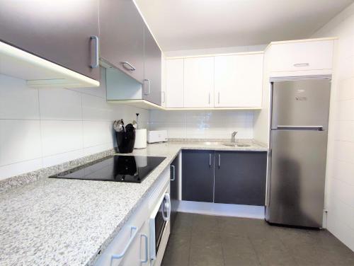 La cuisine est équipée de placards blancs et d'un réfrigérateur en acier inoxydable. dans l'établissement Mendebaldea Suite Premium, à Pampelune