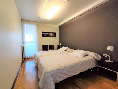 a bedroom with two beds and a large window at Mendebaldea Suite Premium in Pamplona