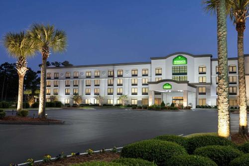 a large white building with palm trees in front of it at Wingate by Wyndham Wilmington in Wilmington