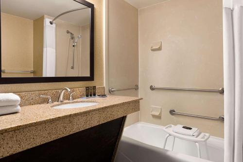 a bathroom with a sink and a tub and a toilet at Wingate by Wyndham Wilmington in Wilmington