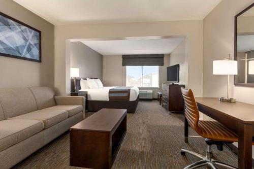 ウィルミントンにあるWingate by Wyndham Wilmingtonのベッドとソファ付きの広いホテルルームです。