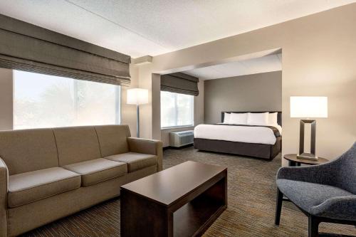 a hotel room with a bed and a couch at Wingate by Wyndham Wilmington in Wilmington