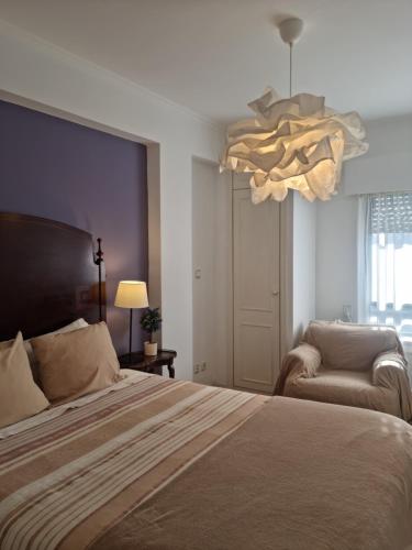 a bedroom with a bed and a chair and a chandelier at Espaçoso apartamento junto ao metro in Lisbon