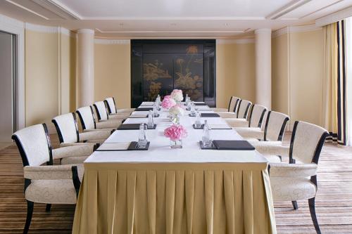 a long table in a room with chairs and flowers at The Peninsula Shanghai in Shanghai