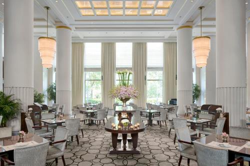 a dining room with tables and chairs and large windows at The Peninsula Shanghai in Shanghai