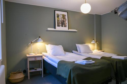 a room with two beds and a table with two lamps at Camp Järvsö Hotell in Järvsö