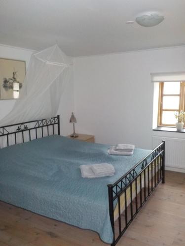 1 dormitorio con cama con sábanas azules y ventana en Lyngsågaard K, en Saeby