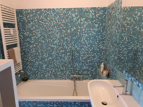 W wyłożonej niebieskimi kafelkami łazience znajduje się wanna i umywalka. w obiekcie Gloriapartment w mieście Civitavecchia