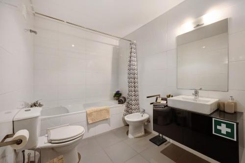 a bathroom with a toilet and a tub and a sink at Apartamento Lusíadas in Portimão