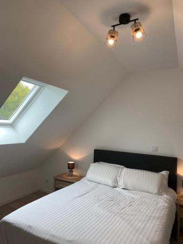 a bedroom with a white bed with a window at amandine in Baguer-Pican