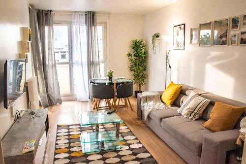 ein Wohnzimmer mit einem Sofa und einem Tisch in der Unterkunft Apartment Villeneuve Stade de France Free parking WiFi in Villeneuve-la-Garenne