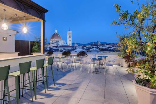 a patio with chairs and a bar with a view of the city at NH Collection Palazzo Gaddi in Florence
