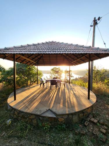 a wooden deck with a table and chairs on it at EZE NOF - A hilltop villa with 360º water view in Nashik