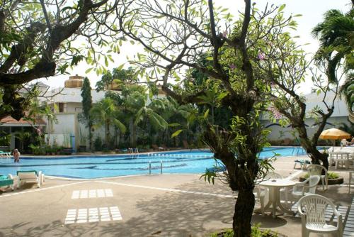 einen Pool mit Stühlen und einem Baum im Vordergrund in der Unterkunft Royal Twins Palace Hotel in Pattaya