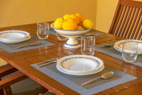 a wooden table with a bowl of lemons and plates on it at Juniper -Inca- in Inca