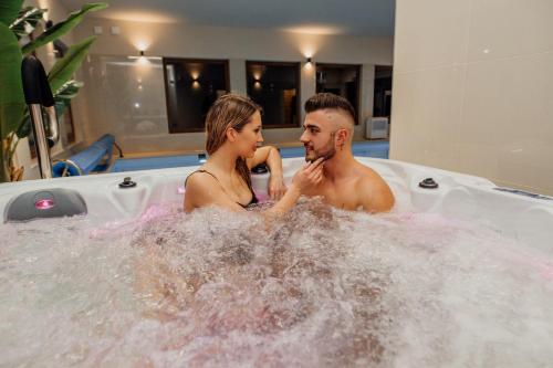 Un uomo e una donna seduti in una vasca idromassaggio di Medical Spa Kwiatowa a Łęczyca