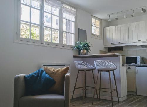 a living room with a couch and a bar with stools at Seashore Hideaway studio in Hermanville-sur-Mer