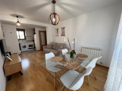 sala de estar con mesa de cristal y sillas blancas en El Llano Zaragoza, en Zaragoza