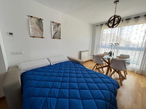 ein Schlafzimmer mit einem großen blauen Bett und einem Tisch in der Unterkunft El Llano Zaragoza in Saragossa