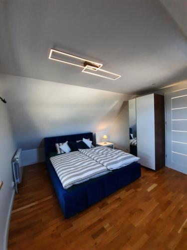 Domek Przy Osadzie في Bieliny: غرفة نوم بسرير ازرق في غرفة ذات أرضيات خشبية