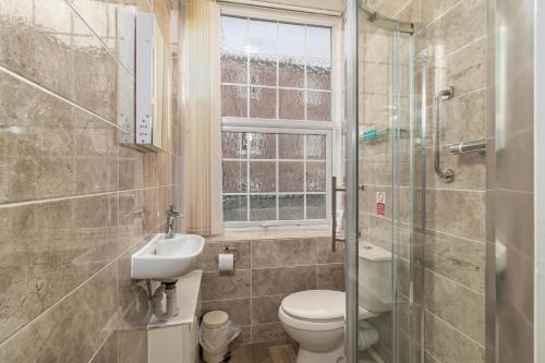 a bathroom with a toilet and a sink and a window at Skegness The Royal Hotel in Skegness