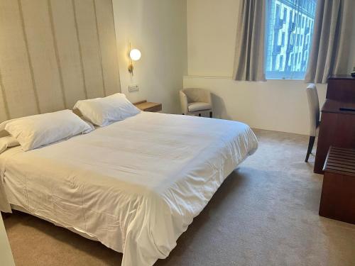 a bedroom with a large white bed and a window at Hotel Oriente in Zaragoza