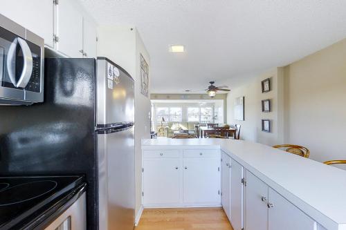 a kitchen with white cabinets and a black refrigerator at Sailing Away in Atlantic Beach