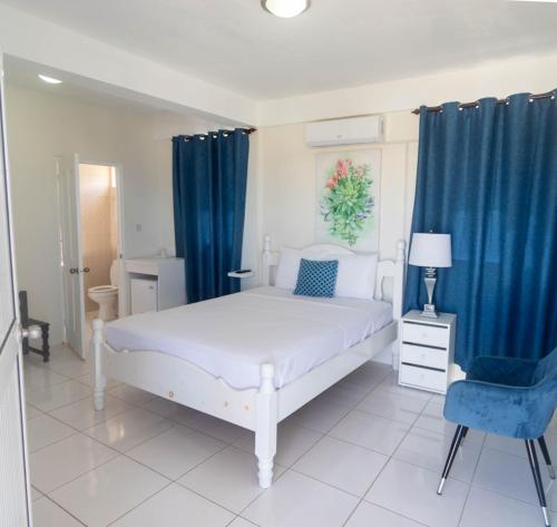 a bedroom with a white bed and blue curtains at St. James Guesthouse in Roseau