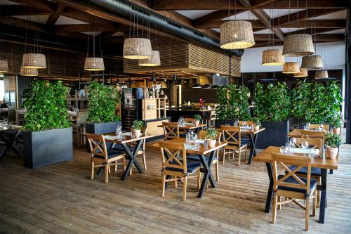 un restaurante con mesas, sillas y macetas en X-BIONIC Hotel, en Šamorín