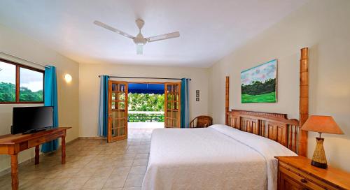 a bedroom with a bed and a flat screen tv at Beach House Condos, Negril in Negril
