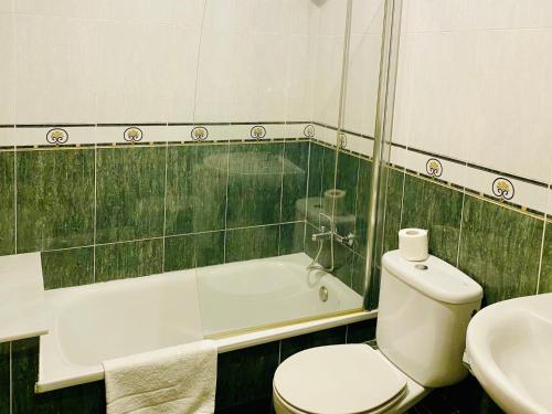 a bath room with a toilet and a bath tub at Hotel Spa Galatea in Burela de Cabo