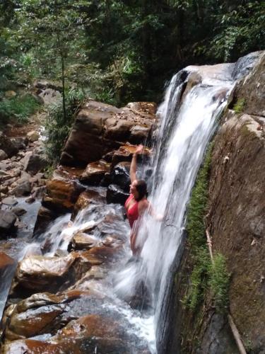 a woman standing on the side of a waterfall at Sinharaja Kurulu Ella Eco Resort in Deniyaya
