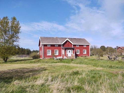 une maison rouge au milieu d'un champ dans l'établissement Sommarö Stugor, à Föglö