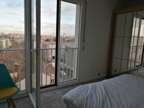 a bedroom with a bed and a balcony with windows at COULEURS & LUMIERES in Reims