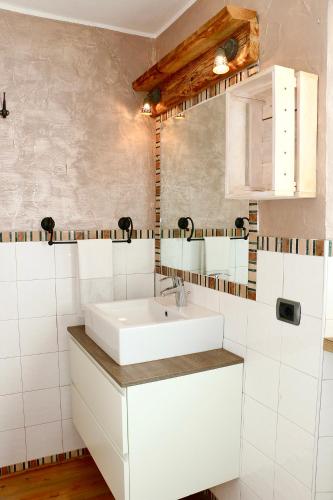 a bathroom with a white sink and white tiles at Appartamenti Diva in Livigno