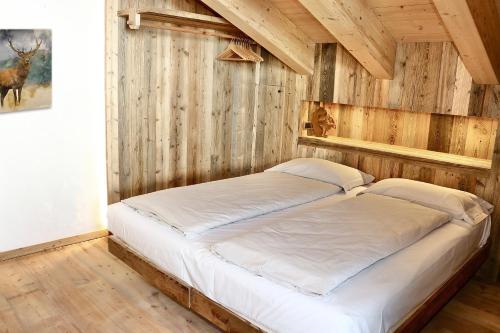 a bed in a room with a wooden wall at Appartamenti Diva in Livigno